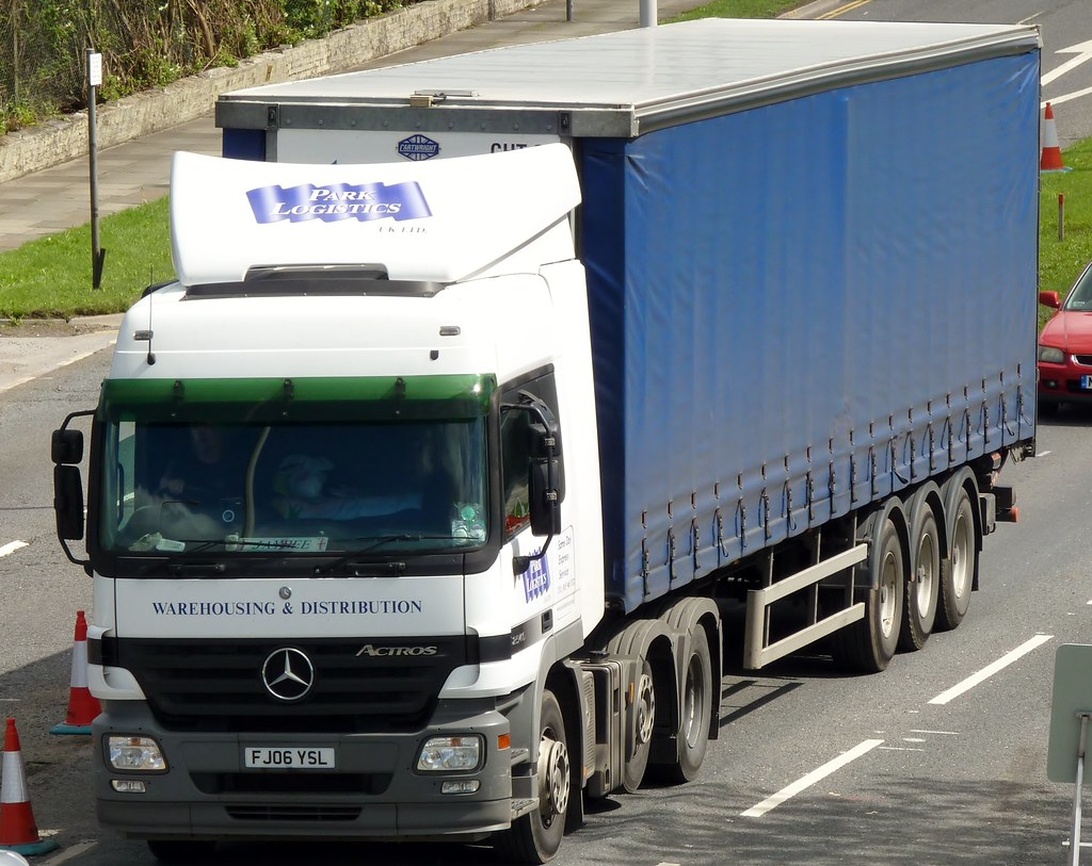 Vit lastbil med blått släp från Park Logistics, specialiserad på lagerhållning och distribution.